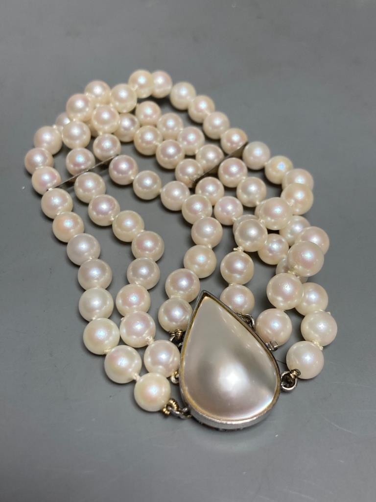 A single strand cultured pearl necklace, with a mother of pearl set 14k white metal clasp, 90cm, gross weight 66.5 grams and matching triple strand bracelet, 18.5cm, gross weight 34.7 grams.